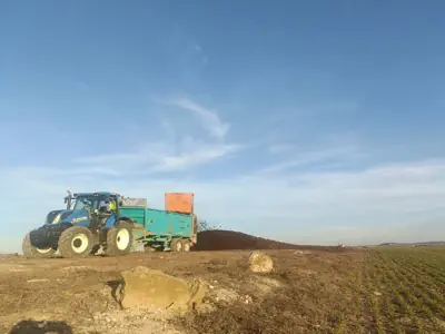 Tractor esparciendo abono en un campo recién labrado